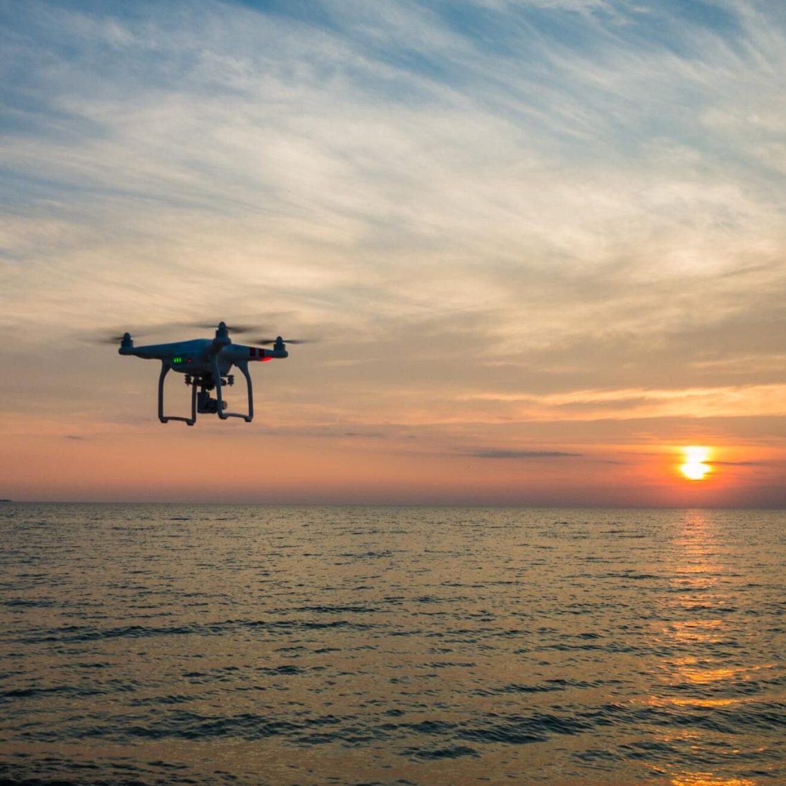 Drone volant au-dessus de l'eau au coucher de soleil.